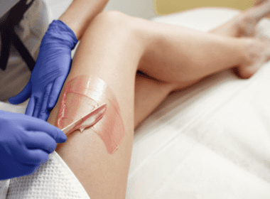 Mujer aplicándose cera para depilarse las piernas